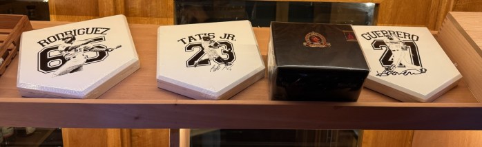 Three signed baseball home plates featuring player names: 'Rodriguez 65', 'Tatis Jr. 23', and 'Guerrero 27', alongside a black box.
